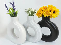 three white and black vases with flowers in them