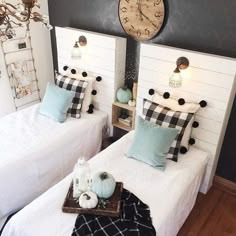 two twin beds in a room with black and white decor on the walls, one has a clock above them