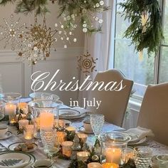 a dining room table set for christmas with place settings and candles in front of it