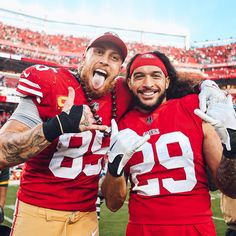 two football players standing next to each other in front of a stadium full of people