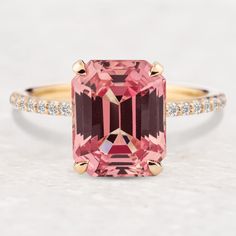 a pink tourmaline and diamond ring on a white surface with gold trimmings