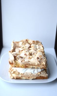 two desserts are sitting on a plate with white frosting and almond toppings