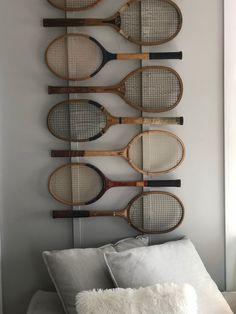 four tennis rackets mounted on the wall above a bed with pillows and throw pillow