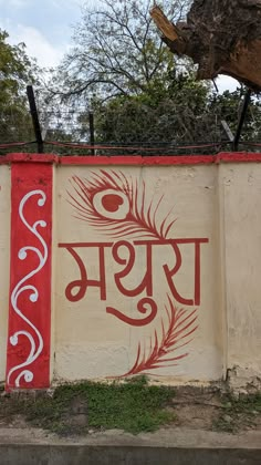 a wall painted with the word india written in red and white on it, next to a tree