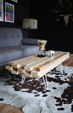 a coffee table made out of wood blocks on top of a cowhide area rug