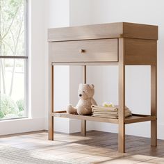 a teddy bear sitting on top of a wooden table next to a window with white walls