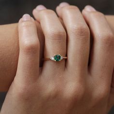 a woman's hand with a green ring on her left and an emerald in the middle