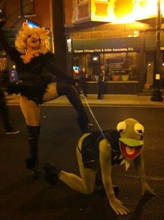 a woman dressed as a frog pulling a man on a skateboard down the street