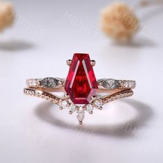 a close up of a ring with a red stone in the middle and two white diamonds around it