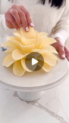 a woman is decorating a white cake with yellow flowers on the top and bottom