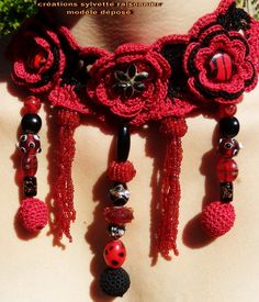 a woman wearing a red crocheted necklace with flowers and beads