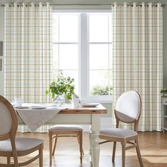 a dining room table with two chairs and a potted plant in the window sill