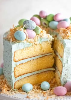 a cake that has been cut in half with easter eggs on top and grass sprinkles around it