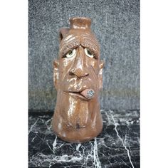 a brown ceramic head with a ring on it's nose sitting on a marble surface