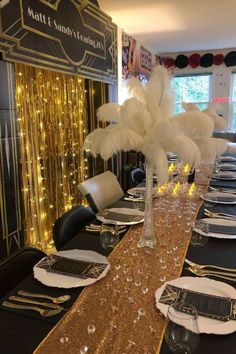 a long table set with black and gold place settings, white plates and silverware