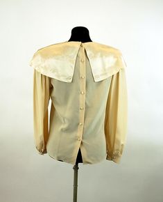 "This is a romantic 1980s blouse made of 100% silk with a large cape collar that is embroidered and features stunning open work. The ivory colored silk is so soft and luxurious! The satin collar gleams in the light. I love the small covered buttons down the back and at the cuffs. It is really an exquisite blouse! Made in the Philippines. Label is Belle Femme by Susan Trout. Size 8. It is generously size, like many blouses from the 80s. Please check measurements. Excellent condition. Measurements Vintage Silk Top For Formal Occasions, Vintage Silk Tops For Formal Occasions, Cream Silk Blouse For Evening, Vintage Satin Blouse For Formal Occasions, Cream Satin Tops For Formal Occasions, Cream Satin Top For Formal Occasions, Vintage Silk Blouse For Formal Occasion, Elegant Cream Blouse With Lace Collar, Silk Cream Evening Blouse