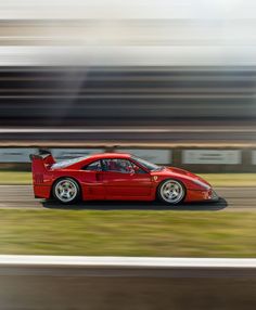 a red sports car driving on a track with grass in the foreground and blurry background