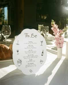 a table set with wine glasses, bread and flowers