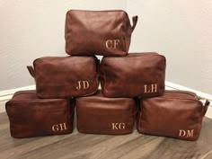 six brown leather bags with initials on them