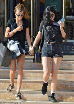 two young women walking down the steps holding shopping bags and looking at their cell phones