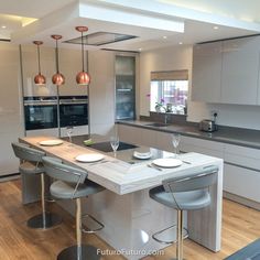 a modern kitchen with stainless steel appliances and bar stools in the center island area