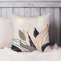 a white pillow with blue and gold leaves on it sitting on a furnishing