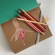 some pencils are sitting on top of a piece of paper with a flower drawn on it