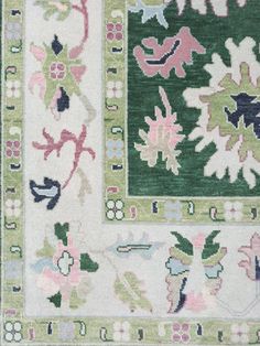 a green and white rug with flowers on the bottom, surrounded by smaller floral designs