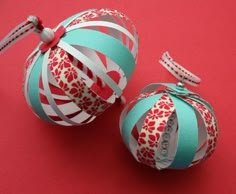 two ornament ornaments on a red surface with ribbon tied around the top and bottom