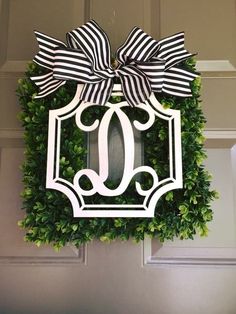 a wreath with a monogrammed letter and bow hanging on the front door to welcome guests