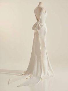 the back of a white wedding dress with a large bow on it's neck