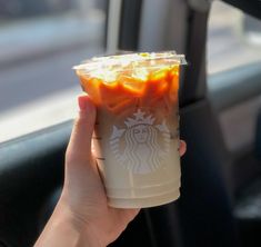 a person holding up a starbucks cup filled with orange jellies in their hand