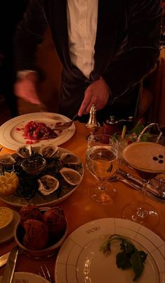 a man in a tuxedo standing over a table filled with plates and food