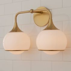 two light fixtures on the wall in a bathroom with white tiled walls and flooring