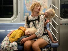 three children are sitting on a subway car and one is holding onto the railing as another child looks at them