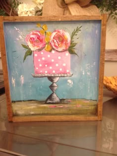 a pink cake sitting on top of a table next to a vase filled with flowers