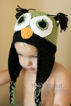 a small child wearing a crocheted owl hat