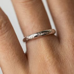 a woman's hand with a wedding ring on her left hand and the word love written in cursive writing on it