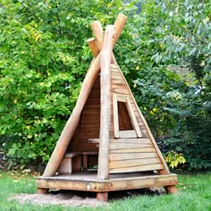 a wooden teepee sitting on top of a lush green field