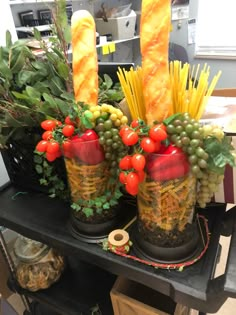 two vases filled with food and vegetables on top of a black table next to other items