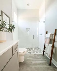 a bathroom with a toilet, sink and shower in it's stall area next to a ladder