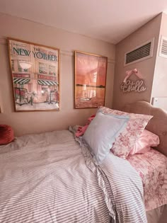 a bedroom with pink and white bedding, pictures on the wall and paintings above it