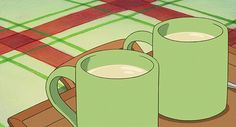 two green mugs sitting on top of a wooden tray