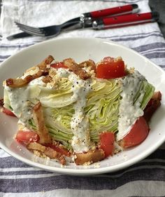 a white plate topped with lettuce and tomato wedges next to a fork