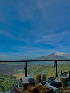 a table with food and drinks on it in front of a view of the mountains