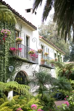 a white house with lots of plants and flowers on the balconies