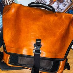 a brown leather bag sitting on top of a wooden table next to a magazine rack