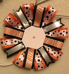 an orange and black ribbon wreath hanging on the wall