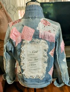 the back of a jean jacket with pink and white patches on it