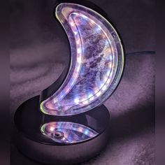 an illuminated object on top of a black stand in the shape of a crescent moon